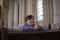 a little boy in prays in a dark catholic church