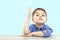 Little boy of preschool age raises his hand to answer the question or ask the question. on an  background