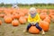 Little boy on a pumpkin farm at autumn. Preschooler child a sitting on huge pumpkin