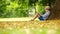 Little boy reading a book sitting at the foot of a big linden tree