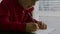 Little boy in a red sweater sitting at a table he is holding a pen in his hands and writing or drawing on a blank white