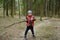 Little boy in red vest is playing with big branch and having fun in forest on early spring day. Outdoor activity for children