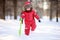 Little boy in red winter clothes having fun with fresh snow