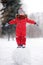 Little boy in red winter clothes having fun with snowman