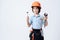 A little boy in repairman form and helmet. Boy holds a adjustable spanner and hammer in his hand.