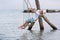 Little boy rides on rope swing on seashore. Swing in the water