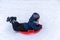 A little boy rides a sled from a winter slide