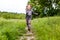 Little boy running down a meadow in a beautiful landscape in summer, very light and happy scene. Curly toddler