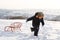 Little boy running through snow with a sled