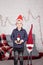 little boy in santa hat near christmas gnome toy, holding dwarf toy in hand in grey room. christmas decor and toys. kids