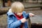 Little boy saws log with a small penknife while walking in the forest at spring or autumn