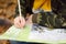 Little boy scout is orienteering in forest. Child is looking on map on background of teepee hut. Adventure, scouting and hiking