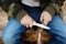 Little boy scout is sharpening a stick with the help knife in the forest