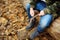 Little boy scout is sharpening a stick with the help knife in the forest