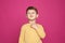 Little boy scratching neck on color background.