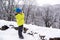 Little boy searching Santa claus house in a mountains. Kid boy using binoculars and having fun on winter walk in forest. Christmas