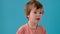 Little boy shakes head in disbelief at bright turquoise wall