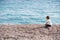 Little boy in shirt sitting on ocean shore watch at seagull in autumn copyspace