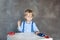 A little boy in a shirt with suspenders plays with toy multi colored toy cars. Preschool boy playing with toy car on a table at ho