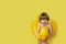 Little boy shouting and hugging rubber duck swimming ring on yellow background