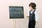 Little boy shows by pointer letters at chalkboard