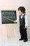 Little boy shows by yellow pointer letters at chalkboard