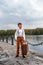 Little boy simpleton in an old-fashioned rustic clothes with a vintage suitcase standing at the arrival station on the pier of the