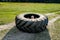 Little boy sits in the center of a large tractor tire from the wheel lying on a country road