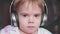 A little boy sits in a chair and listens to music through headphones. Face close up