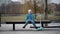 A little boy sits on a park bench, a child rests after riding a scooter