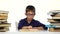 Little boy sits at a table and reads the book slowly. White background