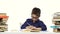 Little boy sits at a table and reads the book slowly. White background