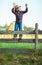 Little boy sits on wooden fence against picturesque haystack