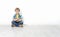 Little boy sitting on floor leaning against wall