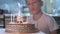 little boy sitting at kitchen table next to birthday cake with lighted candles