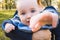 Little boy is sitting on moms hands and reaches for camera at outdoor