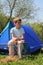 Little boy sitting near blue tent on nature