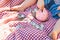 Little Boy Sitting on Picnic Blanket Puts Coins in Piggy Bank