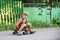 A little boy is sitting on a skateboard near the house on the road.