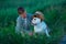 Little boy sitting standing with his english bull dog on the meadow of green rye. Handsom kid posing with best friend wearing