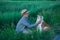 Little boy sitting standing with his english bull dog on the meadow of green rye. Handsom kid posing with best friend wearing