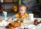 Little boy sitting at the table eating stretches to delicious candy