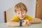 Little boy sitting at the table and looking smart watch. Smart watch for baby safety. The child makes school lessons