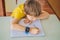 Little boy sitting at the table and looking smart watch. Smart watch for baby safety. The child makes school lessons