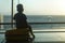 Little boy sitting on a yellow suitcase at the airport and looking at the plane