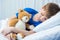 Little boy sleeping in hospital bed with teddy bear