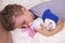 Little boy sleeps on a fluffy bedspread, hugging a teddy bunny