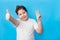 little boy smiling joyfully and looking happy, feeling carefree and positive, holding both thumbs up on blue background