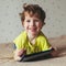 Little boy smiling and looking at tablet, using modern technology. Square photo