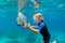 Little boy in snorkeling mask dive underwater with tropical fishes